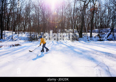 Jungen spielen Eishockey auf Eisbahn Stockfoto