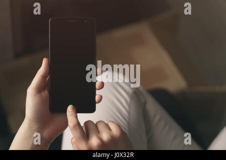 Weibliche Teenager Hand holding Smatphone im Innenbereich mit leeren Bildschirm und machen die Authentifizierung per Fingerabdruck Stockfoto