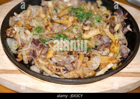 Bratkartoffeln mit kleinen Stücken von Fleisch auf den Teller. Stockfoto