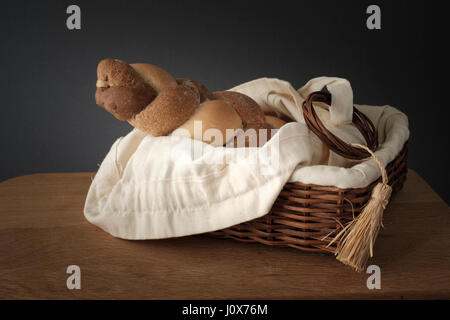 3 Typen, die verwobenen Brot in einem Weidenkorb auf einem Holztisch steht Stockfoto