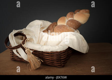 3 Typen, die verwobenen Brot in einem Weidenkorb auf einem Holztisch steht Stockfoto