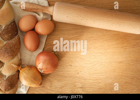 geflochtene Brot mit Zwiebeln, Eiern und Nudelholz auf einem Holztisch mit Textfreiraum, Food-Konzept Stockfoto