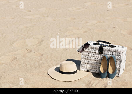 Sommer-Urlaub am Meer. Weiße Weide Koffer und Damen Accessoires und Schuhe am Strand. Selektiven Fokus. Stockfoto