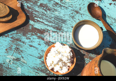 Tonkrug, eine Tasse Milch, Quark und Brot auf einem Tisch von leichten blauen Platten. Ansicht von oben Stockfoto