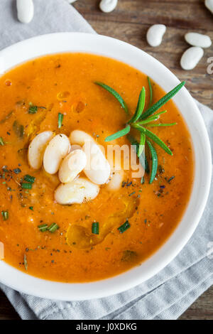 Cremige weiße Bohnen und Gemüsesuppe mit Rosmarin auf hölzernen Hintergrund - gesunde hausgemachte vegetarische vegane Suppe essen Diätkost Stockfoto