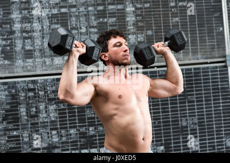 Muskulöse Sportler tun Gewichte heben ein paar Hanteln über seine Schultern in eine Nahaufnahme Oberkörper training Stockfoto