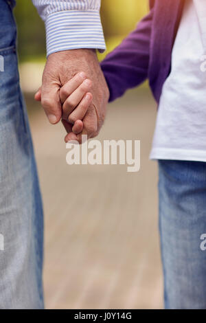 Ältere und junge Hand in Hand wandern in der Natur Stockfoto