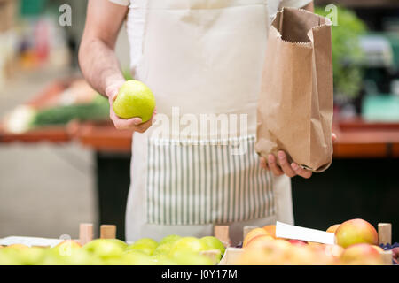 Verkäufer bietet einen Apfel am Markt Shop Stockfoto