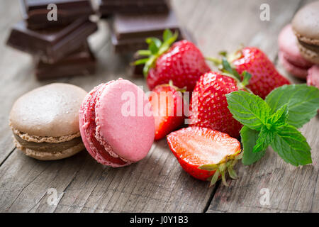 Früchte-Macarons auf einer Holzplatte mit Erdbeer und Schokolade Stockfoto