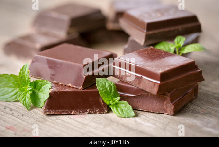 Stack Schokoladenstücke mit einem Blatt Minze auf hölzernen Hintergrund Stockfoto