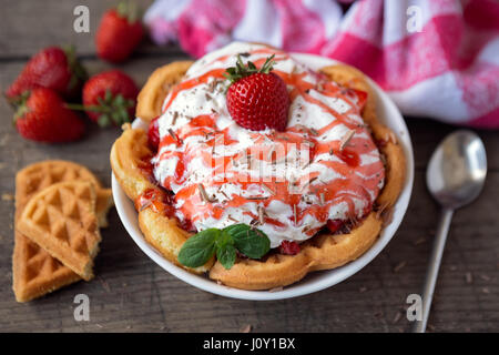 Goldene Waffeln garniert mit frischen in Scheiben geschnittenen Erdbeeren und Sahne Stockfoto