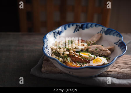 Salat mit Huhn, Kürbis, Bohnen und Wachteleier in waagerechter Schüssel Seite Ansicht Stockfoto