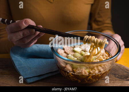 Frau, Essen mit Stäbchen-Ramen-Nudeln mit Huhn und Sellerie horizontale Stockfoto