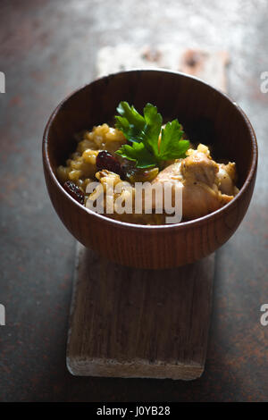 Pilaf mit Reis und Huhn, Rosinen in einer Holzschale vertikalen Stockfoto