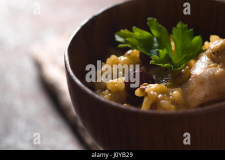 Pilaf mit Reis und Huhn, Rosinen in einer Holzschale Closeup horizontale Stockfoto
