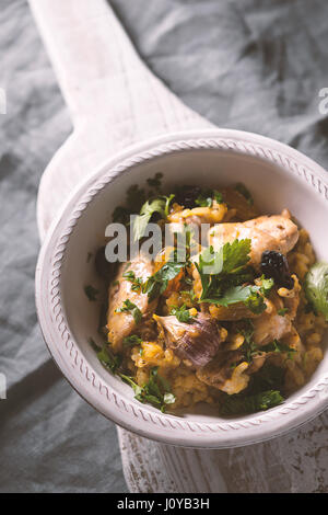 Pilaf mit Reis und Huhn, Rosinen in einer Keramikschale auf der vertikalen Ständer Stockfoto