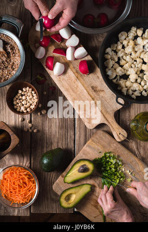 Zubereitung Salat aus Rettich, Kichererbsen, Avocado und Karotte vertikale Stockfoto