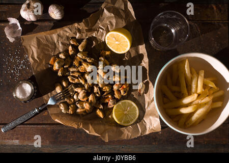 Muscheln mit Zitronen und Pommes frites in der Draufsicht Metall Hintergrund Stockfoto