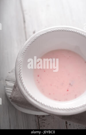 Fruchtjoghurt in die weiße Platte auf dem vertikalen weißen Holztisch Stockfoto