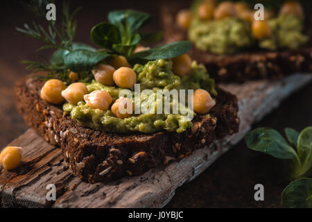 Open-Sandwich mit Avocado Creme und Grüns auf dem Holzbrett Stockfoto