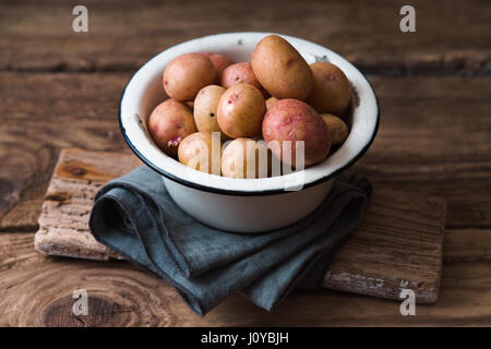 Rohe Kartoffeln in die Metallschale auf dem Holztisch Stockfoto