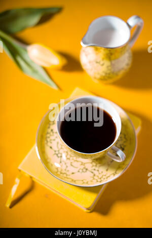 Tasse mit Kaffee, Notebook, Tulpe auf gelbem Hintergrund Stockfoto