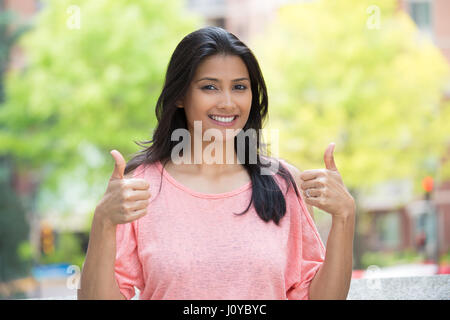 Closeup Portrait von junge hübsche Frau im rosa Hemd mit zwei Daumen hoch Zeichen Geste, isoliert im freien Hintergrund. Positive Emotionen Gesichtsausdruck Stockfoto
