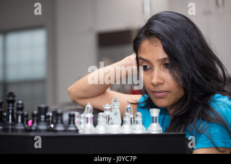 Closeup Portrait, denken Frau im blauen Hemd Schachspielen, Fragen, nächsten Schritt, isoliert im Innenbereich background Stockfoto