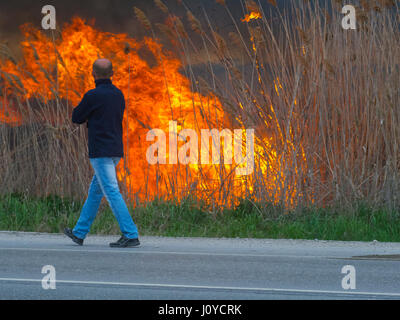 Ein Mann spaziert entlang der Straße in der Nähe eines Feuers Stockfoto