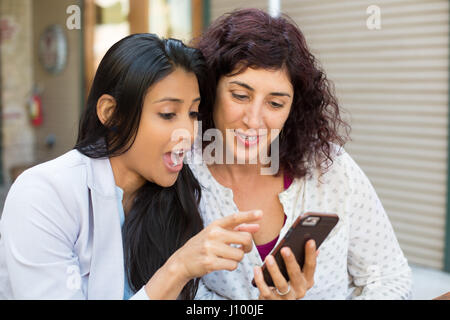 Closeup Portrait zwei überrascht Mädchen Blick auf Handy diskutieren neueste Klatsch News, isoliert einkaufen, schockiert, was sie sehen, im freien backgr Stockfoto