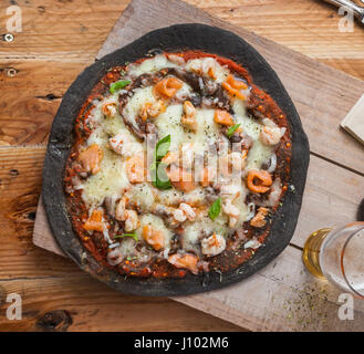 Pizza mit Meeresfrüchten schwarz: Lachs, Garnelen, Muscheln. Stockfoto