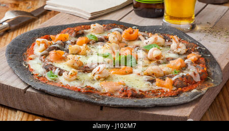 Pizza mit Meeresfrüchten schwarz: Lachs, Garnelen, Muscheln. Stockfoto