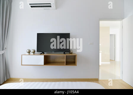 Moderne leere Schlafzimmer mit led-tv auf weiße Wand und Holzregal Stockfoto