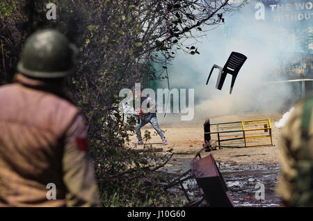 Srinagar, Kaschmir. 17. April 2017. Kashmiri Student wirft einen Stuhl bei der indischen Polizei während einer Protestaktion außerhalb einer Hochschule in Srinagar, Sommer in der Hauptstadt von Kaschmir, 17. April 2017. Dutzende von Menschen, meist Studenten, wurden bei frischen Anti-Indien Proteste und Auseinandersetzungen mit Regierungstruppen in unruhigen Kaschmir am Montag verletzt. Bildnachweis: Javed Dar/Xinhua/Alamy Live-Nachrichten Stockfoto