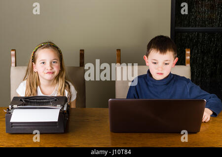 jungen und Mädchen arbeiten auf alten Schreibmaschine und laptop Stockfoto