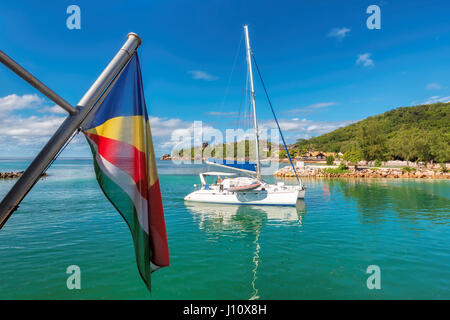 Tropischen Insel mit Segelyacht und Flagge der Seychellen. Stockfoto