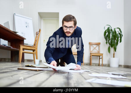 Porträt des mittleren Alter bärtiger Mann mit Brille auslegen Dokumente im Stock im Büro Stockfoto