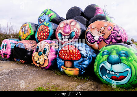 Haybales gestapelt an der Seite einer Straße mit verschiedenen bunten Flächen und Objekte auf ihnen gemalt werden. Stockfoto