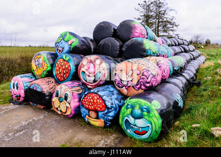 Haybales gestapelt an der Seite einer Straße mit verschiedenen bunten Flächen und Objekte auf ihnen gemalt werden. Stockfoto