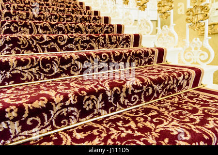 Messing Stairrods rot gemustert Axminster Teppich auf der Treppe eines noblen Hauses gedrückt. Stockfoto