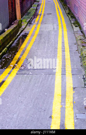 Doppelte gelbe Linien auf beiden Seiten eine sehr schmale Straße. Stockfoto
