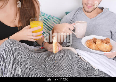 Schöne junge Paar im Bett zu frühstücken. Im Innenbereich. Stockfoto