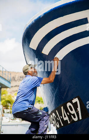 PUERTO DE MORGAN, Spanien - 3. Mai 2016: Unidentified Fischer Malerei sein Boot in Puerto de Mogan, Gran Canaria, Spanien. Puerto de Mogan ist wichtig Stockfoto