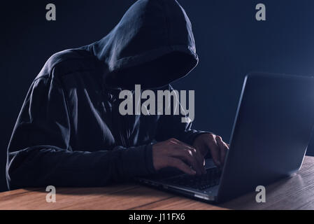 Cyber-Kriminalität und Computer-Virus Konzept mit Kapuzen gesichtslose Person auf laptop Stockfoto