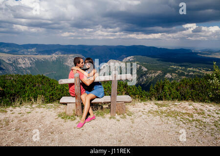 verbinden Sie reisen und entspannen Sie sich in Bergen. Paar sitzen auf Bank. Hinten Sie Ansicht von. Montenegro, Durmitor Stockfoto