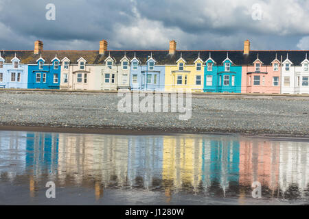 Eine Reihe von bunten Häusern am y Borth, an der Cardigan Bay, spiegelt sich auf dem nassen Strand Stockfoto