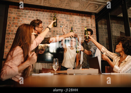 Gruppe von erfolgreichen jungen Geschäftsleute mit Bier zu feiern. Heterogene Gruppe von Menschen, die Getränke über erfolgreichen Geschäftsabschluss. Stockfoto