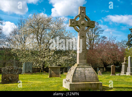 Keltisches Kreuz auf Grab und Grabsteinen im alten Kirchhof mit blauem Himmel an einem Frühlingstag, Crichton Collegiate Church, Midlothian, Schottland, UK Stockfoto