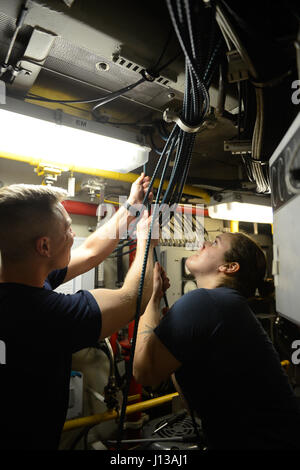 Das Personal der Küstenwache ersetzt einen defekten Steuerbord-Notbremsdraht im Maschinenraum des Cutter Tiger Shark, um die volle Bremsleistung der Schiffsmotoren und die Betriebssicherheit zu gewährleisten. Stockfoto
