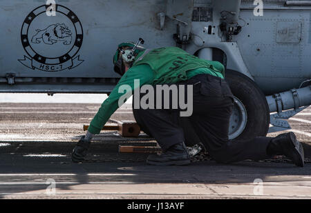 170412-N-QI061-065 Atlantik (12. April 2017) Luftfahrt Elektriker Mate 2. Klasse Daniel Henson aus Austin, Texas, Unterlegkeile entfernt und Ketten aus einem MH-60 s Sea Hawk Hubschrauber zugewiesen, die staubigen Hunde der Hubschrauber Meer bekämpfen Squadron (HSC) 7 auf dem Flugdeck des Flugzeugträgers USS Dwight D. Eisenhower (CVN-69) (Ike). Ike und seine Fördermaschinegruppe Streik beteiligen sich eine Sustainment Übung Aufrechterhaltung der Bereitstellung Bereitschaft im Rahmen von der optimierten Flotte Antwort planen (OFRP) im Gange. (Foto: U.S. Navy Mass Communication Specialist 3. Klasse Nathan T. Beard) Stockfoto